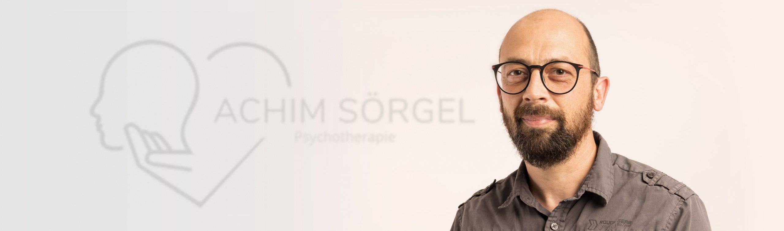 Porträt von Achim Sörgel, im Hintergrund dezent das Praxislogo